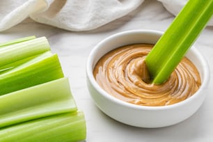 a bowl of peanut butter and celery sticks