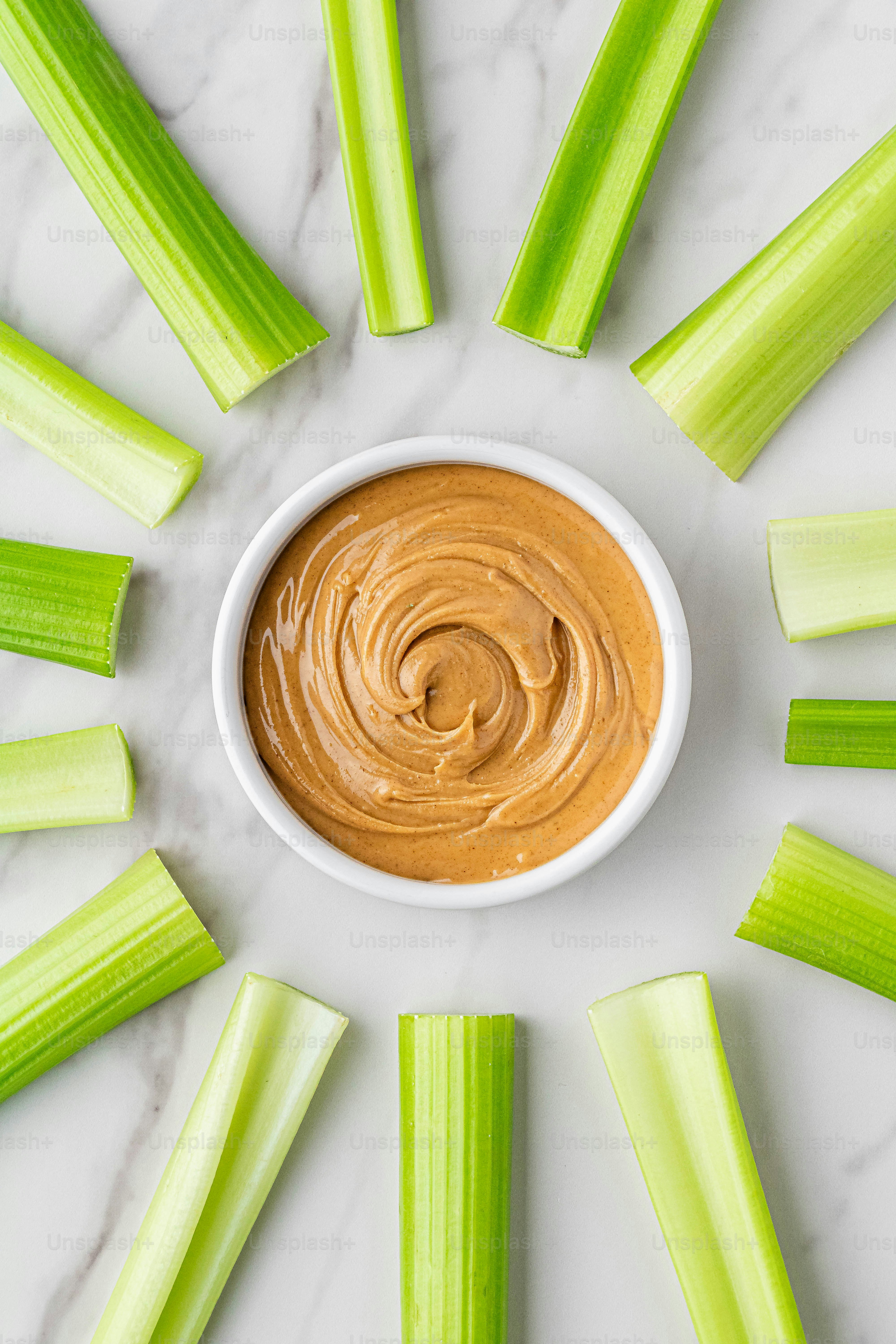 Selleriestangen um eine Schüssel Erdnussbutter angeordnet