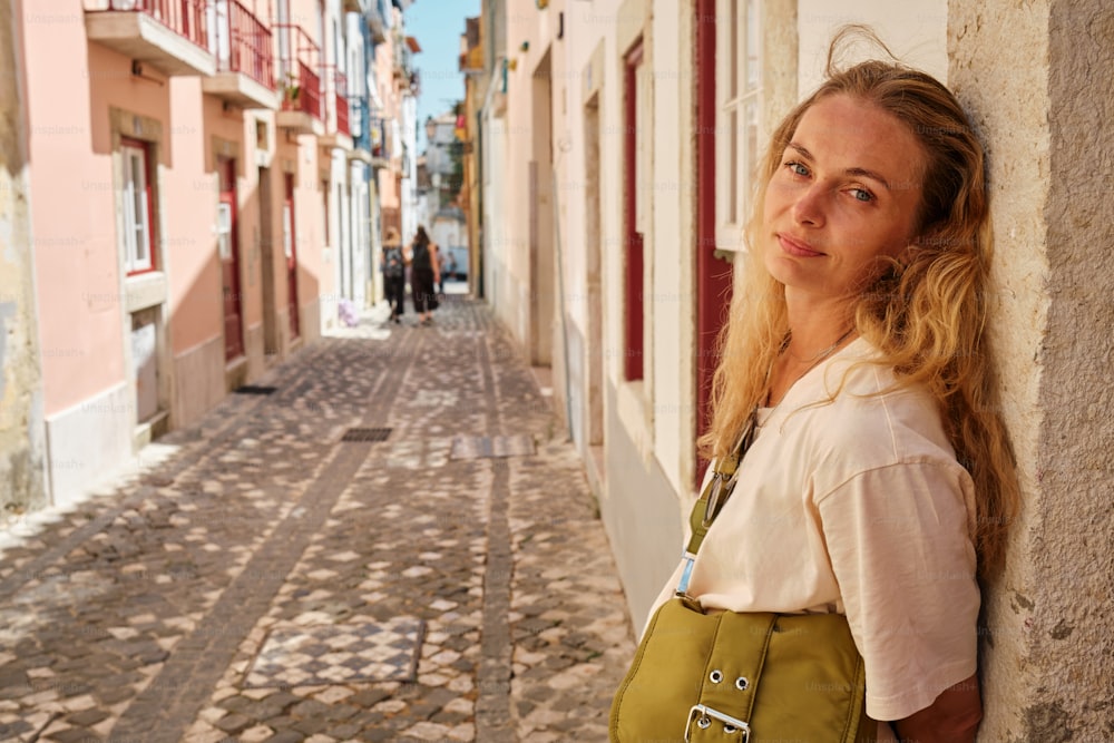 a woman leaning against a wall on a cobblestone street