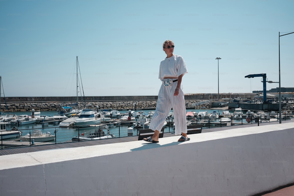 a person standing on a ledge near a marina