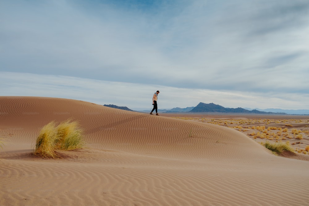 a man standing on top of a sand dune