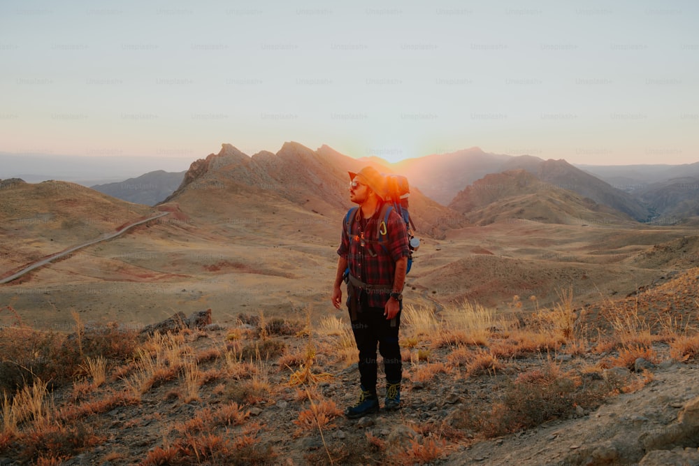 a man with a backpack standing on a hill