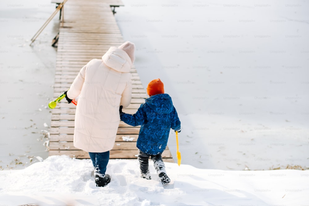 a woman and a child are walking in the snow
