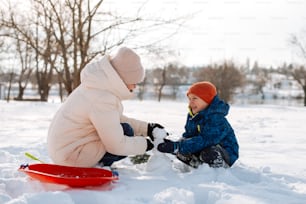 un petit garçon jouant avec un bonhomme de neige dans la neige