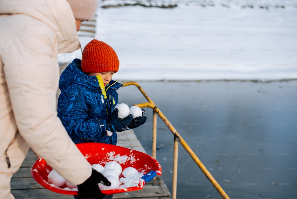 a woman and a child are playing with snowballs