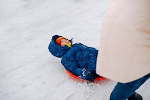 a small child laying on a sled in the snow