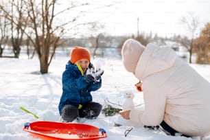 a young child playing with a snowman in the snow