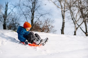a young boy riding a snowboard down a snow covered slope