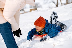 a young boy laying in the snow next to a woman