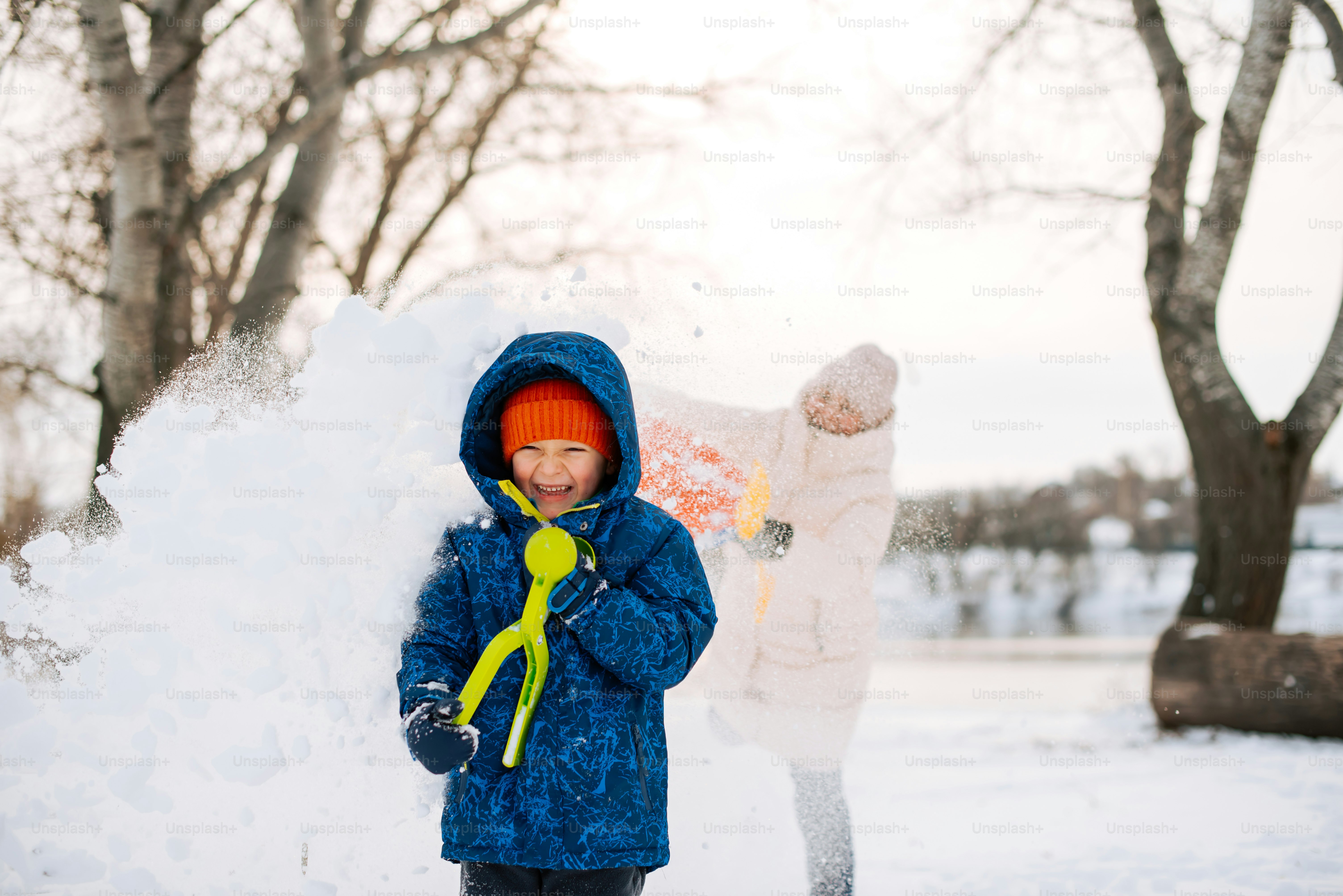 a young boy playing in the snow with a snow blower