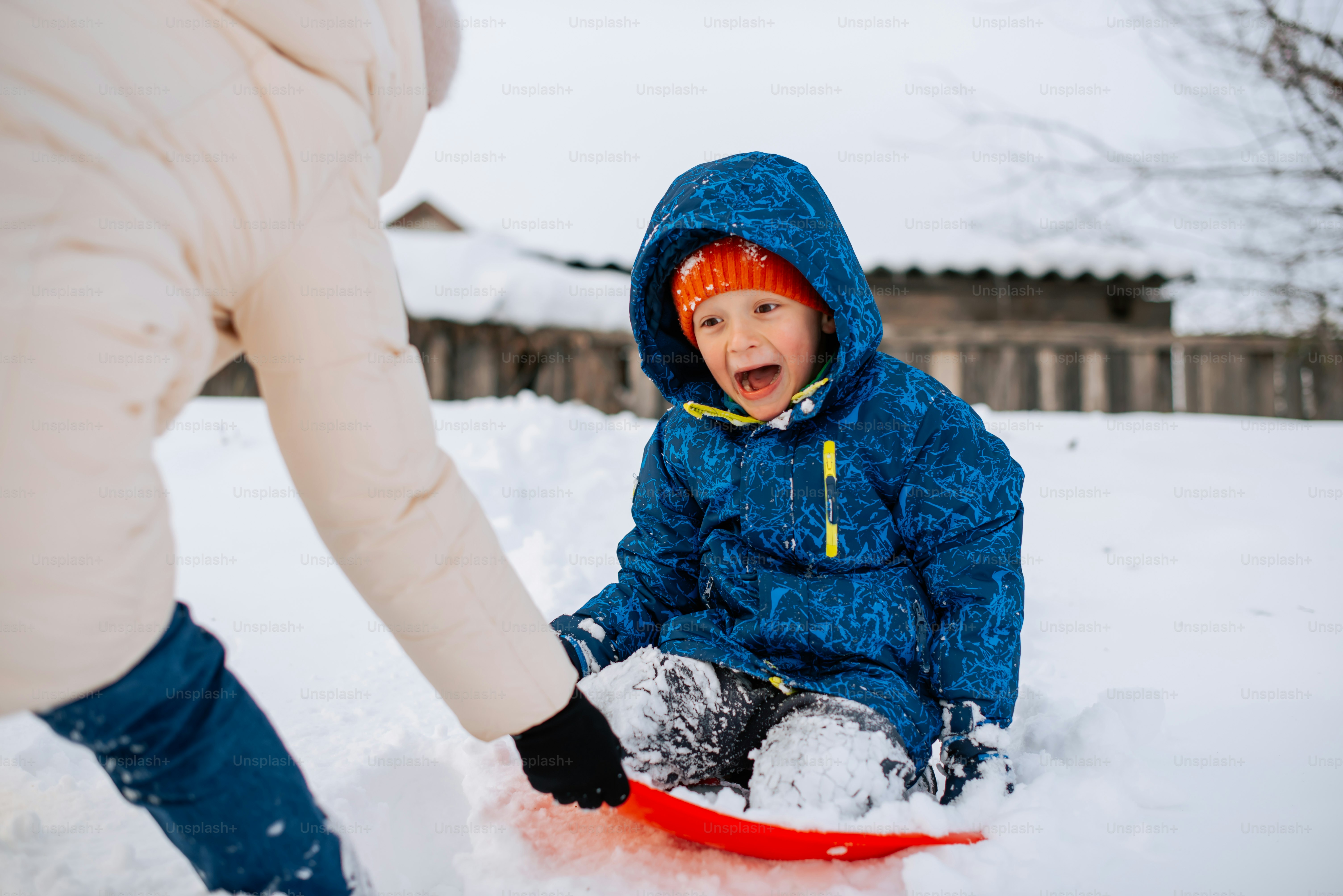 a young child sitting in the snow on a sled