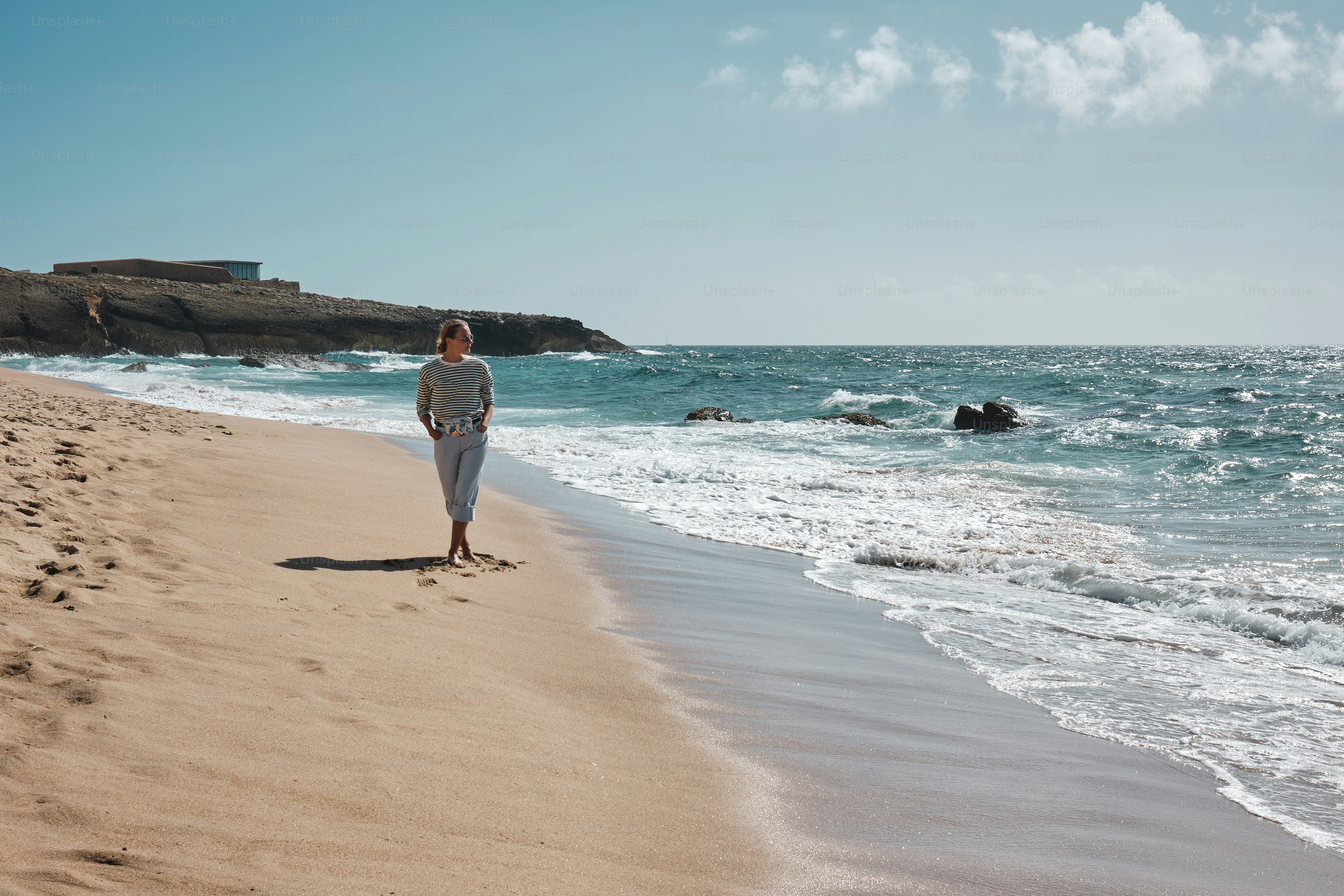 A woman standing on top of a cliff next to the ocean photo – Travel ...