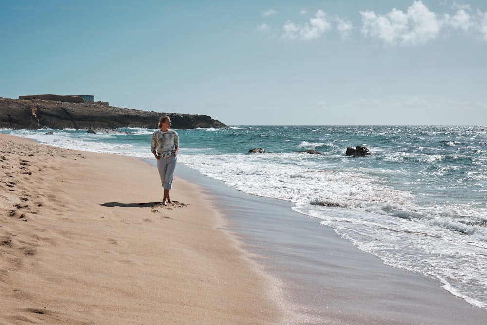 una mujer caminando por una playa junto al océano