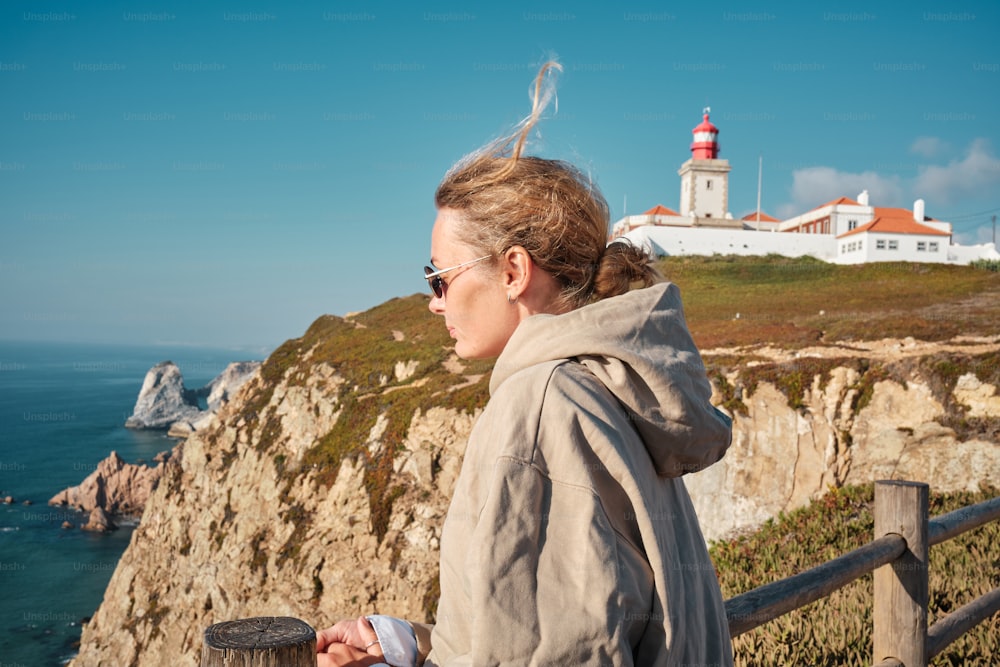 a woman standing on top of a cliff next to the ocean