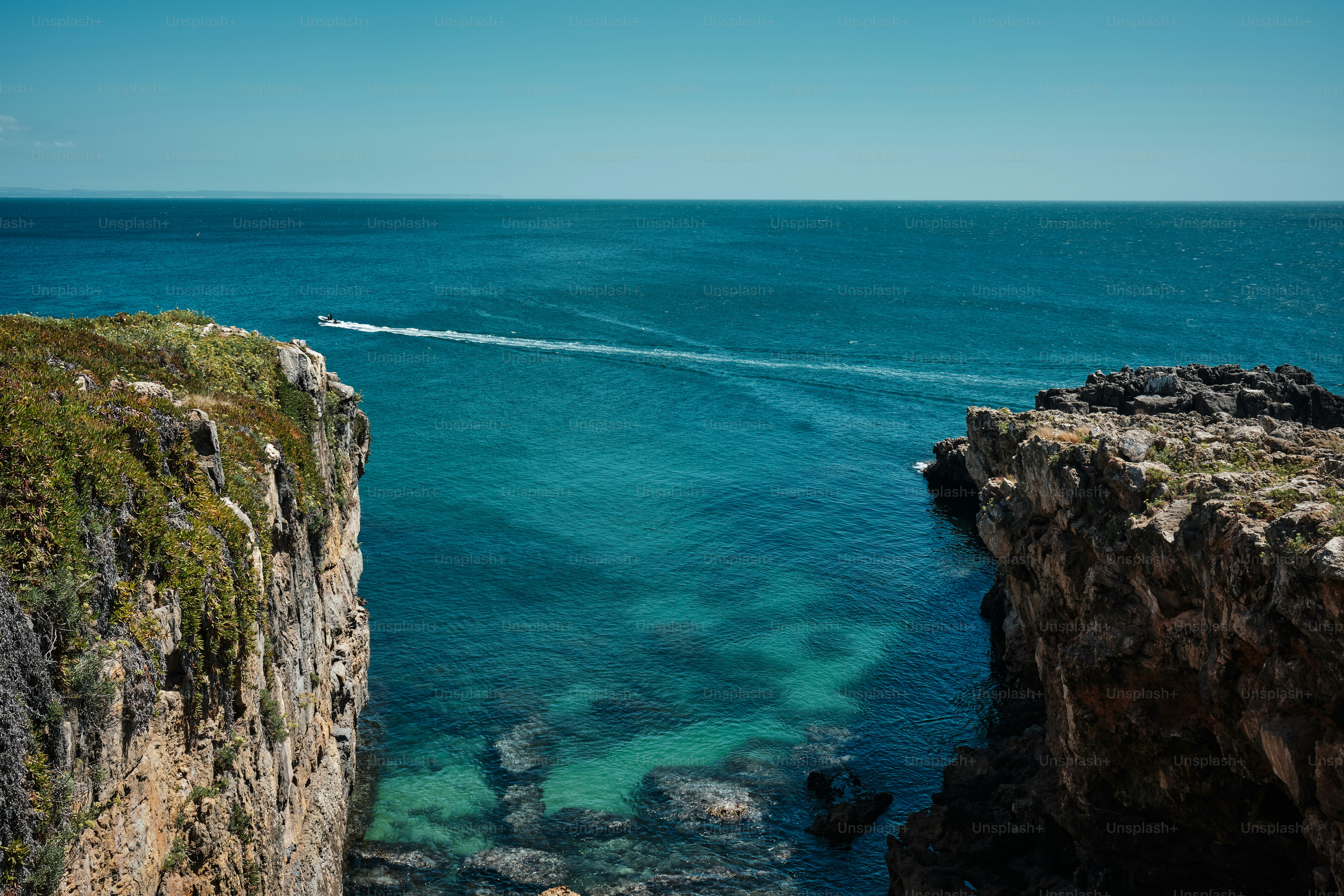 um barco está na água perto de um penhasco