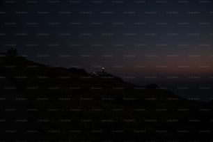 une colline surmontée d’un phare la nuit