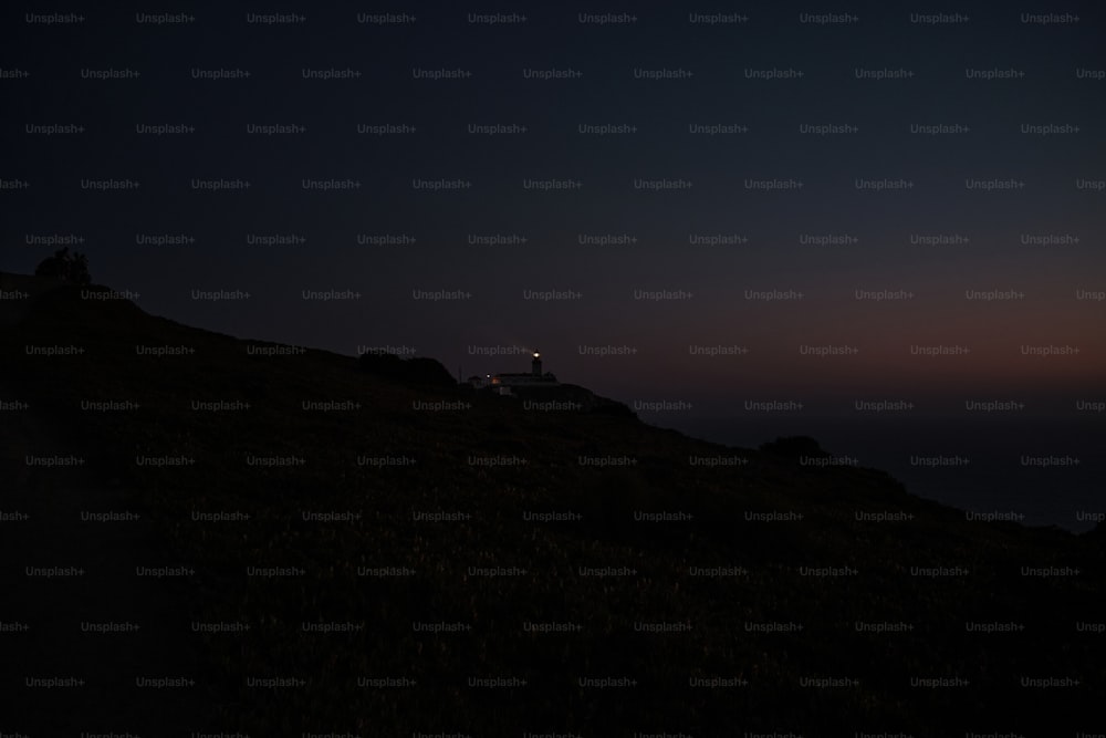 a hill with a lighthouse on top of it at night
