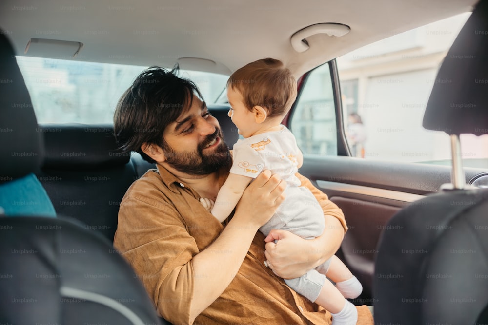 a man holding a baby in the back seat of a car