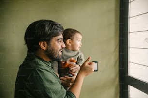 a man holding a baby looking out a window