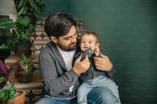 un homme tenant un bébé et jouant avec une télécommande