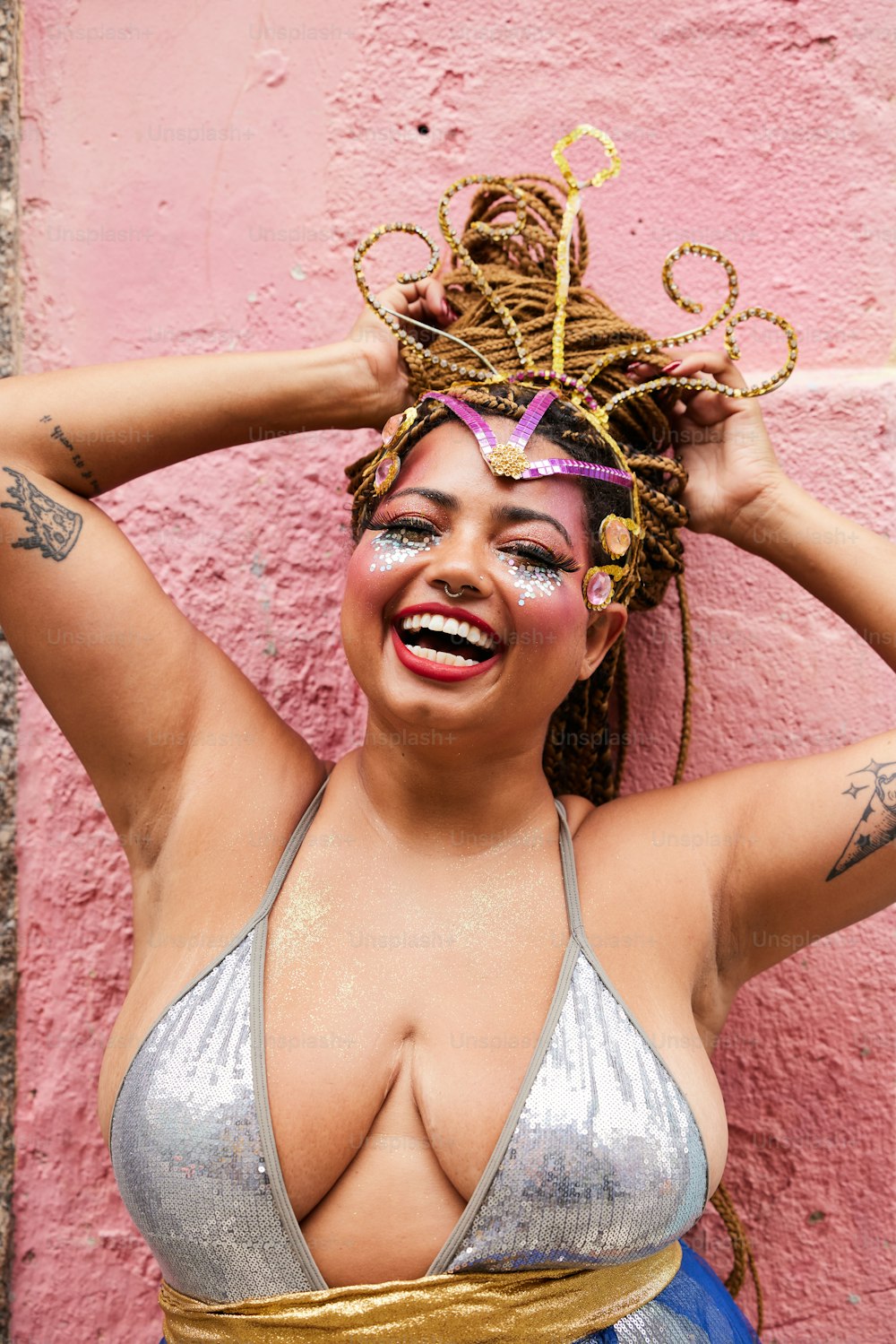 a woman in a silver bikini top with a gold crown on her head