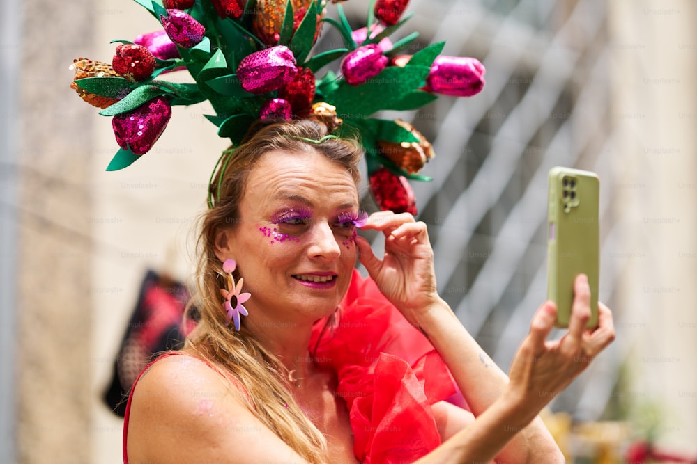 une femme en robe rouge prenant une photo avec un téléphone portable