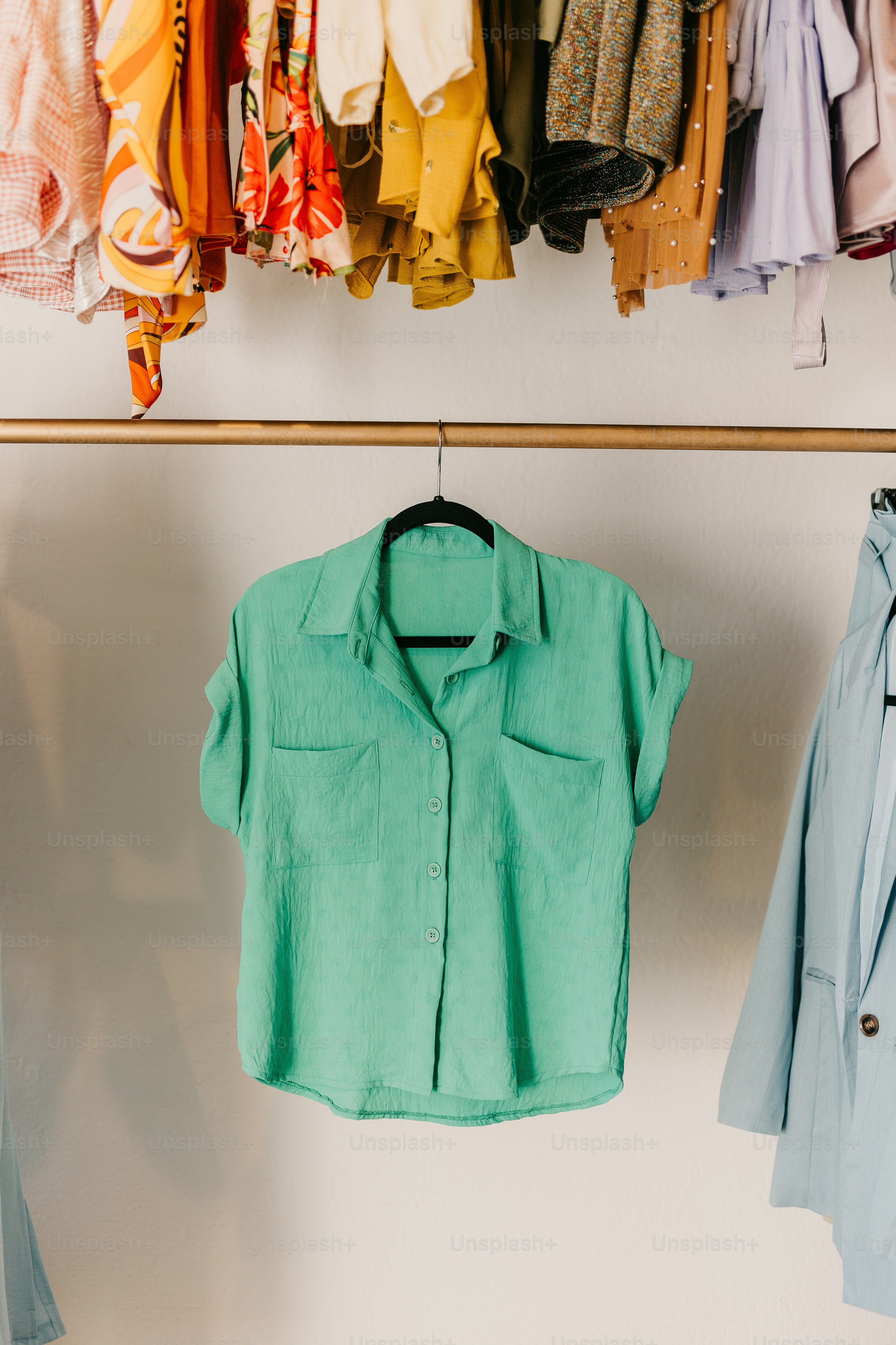 a green shirt and a blue shirt hanging on a rack