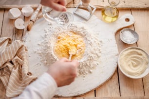 a person pouring flour into a bowl on top of a table