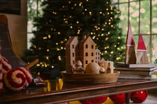 Un árbol de Navidad está en el fondo detrás de un modelo de madera de una casa