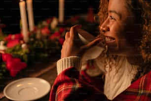 a woman drinking from a cup in front of a christmas table