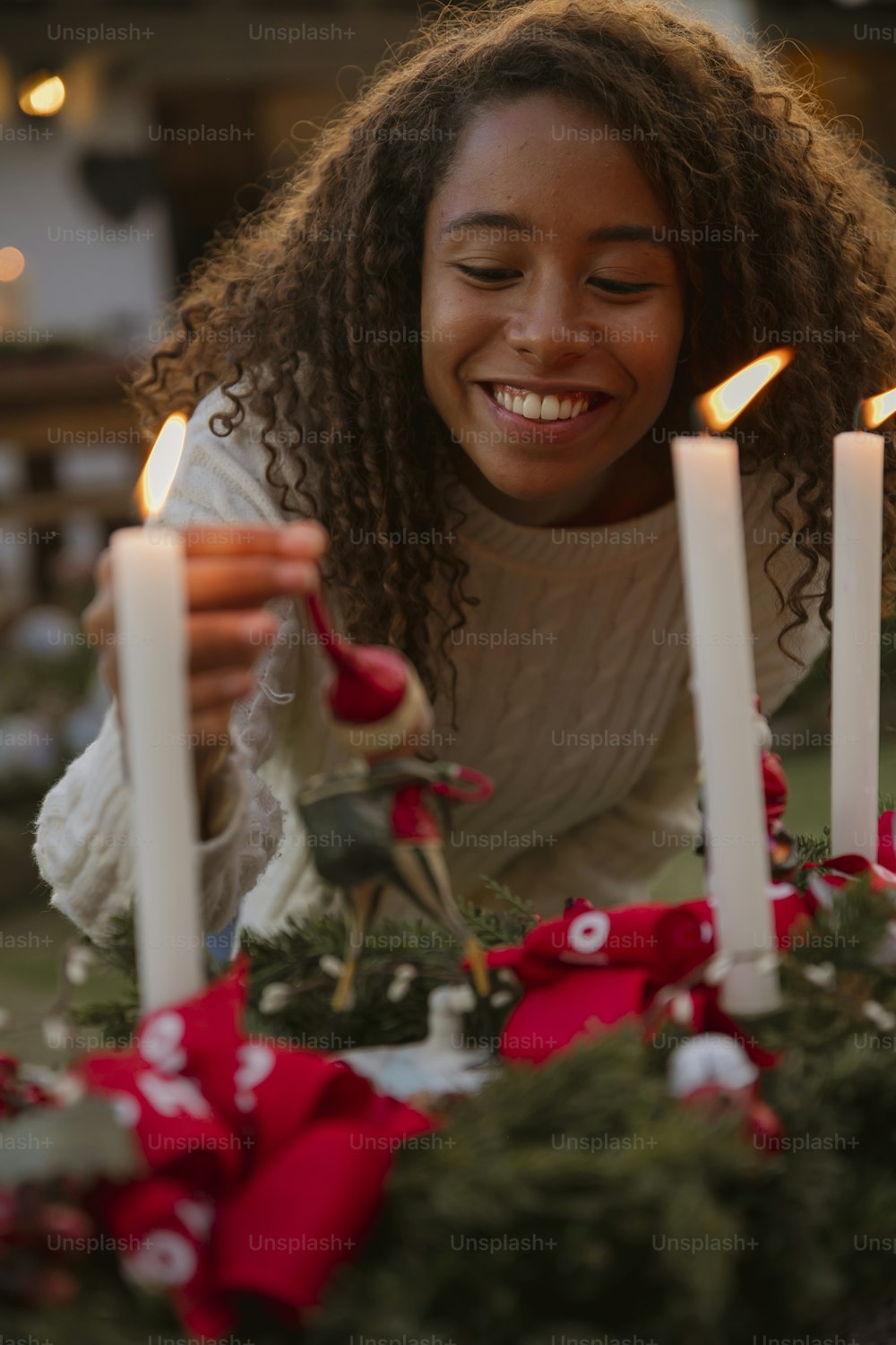 a woman smiles as she lights a candle