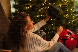 Una donna seduta davanti a un albero di Natale