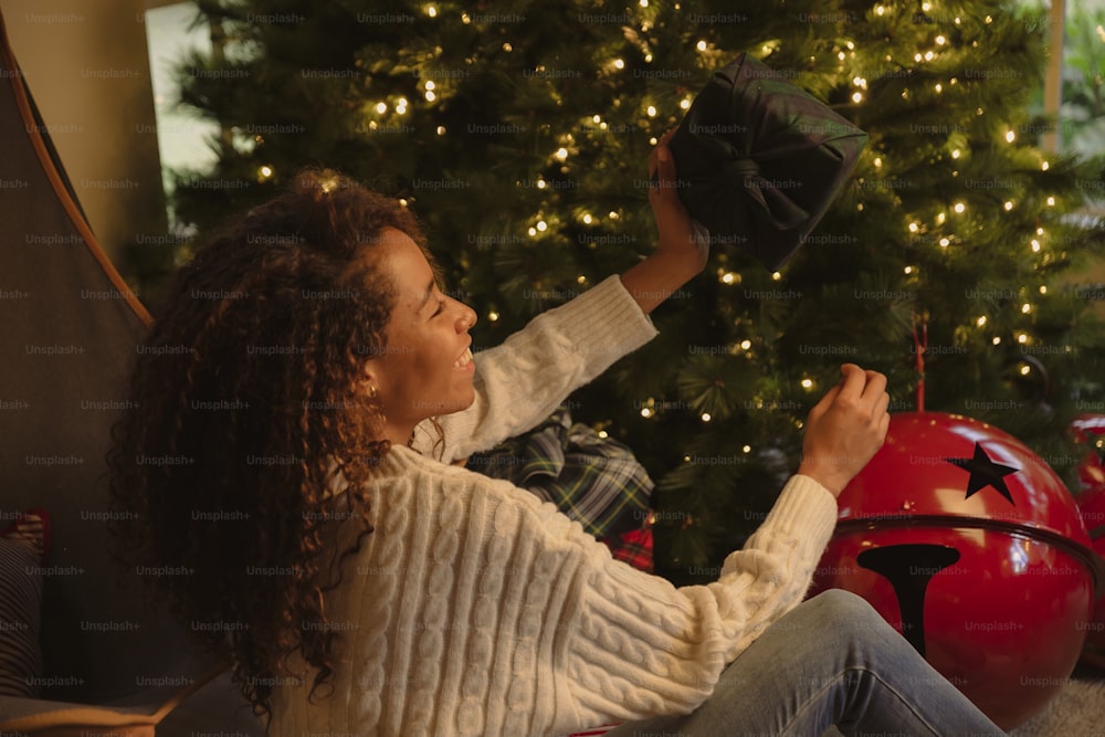 a woman sitting in front of a christmas tree