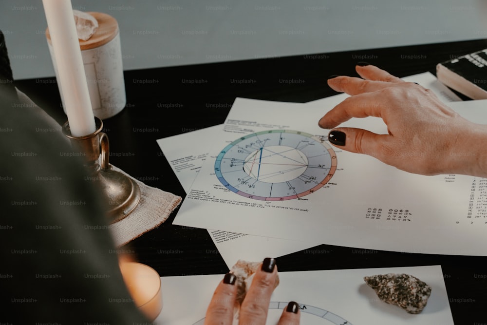 a person sitting at a table with some papers and a candle