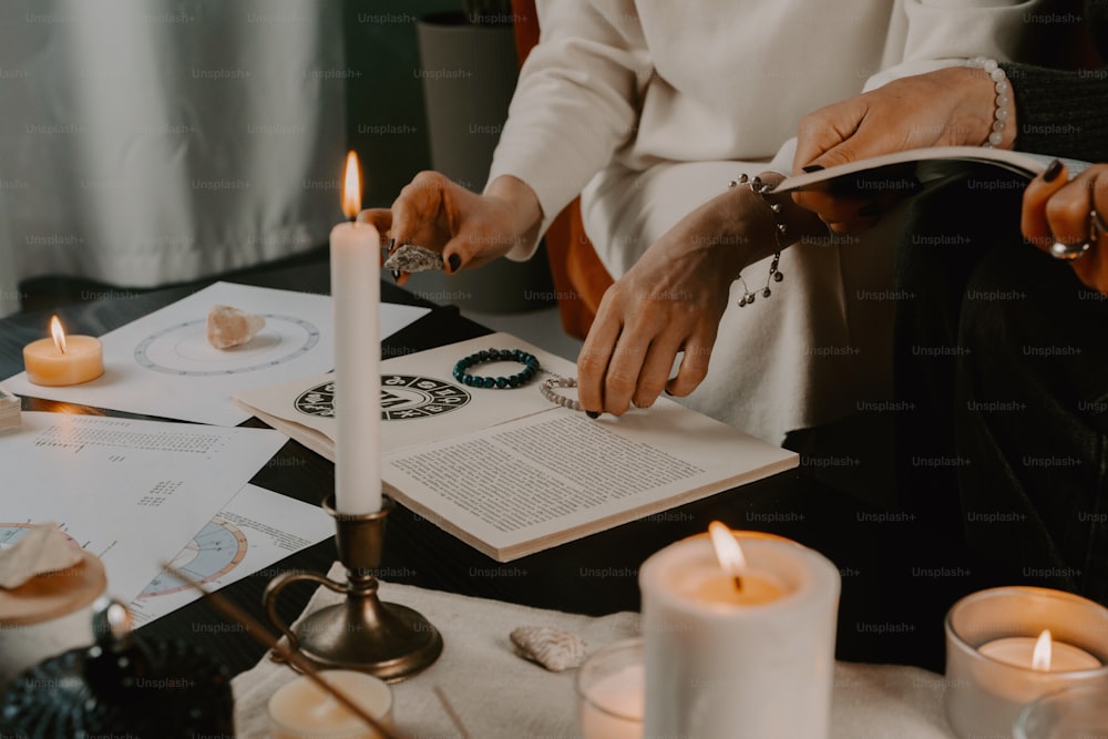 a person sitting at a table with a book and candles