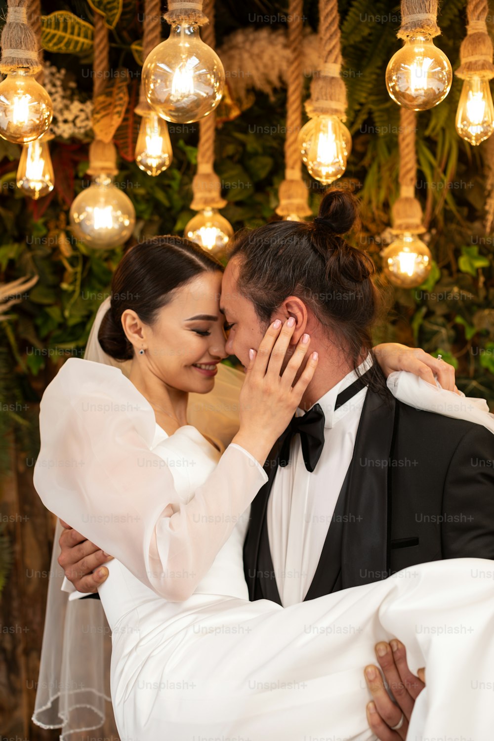 a bride and groom embracing each other under a chandelier
