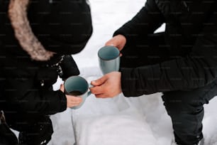 two people holding cups in their hands in the snow