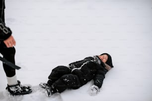 スキーを履いている人の隣で雪の中に寝そべっている人