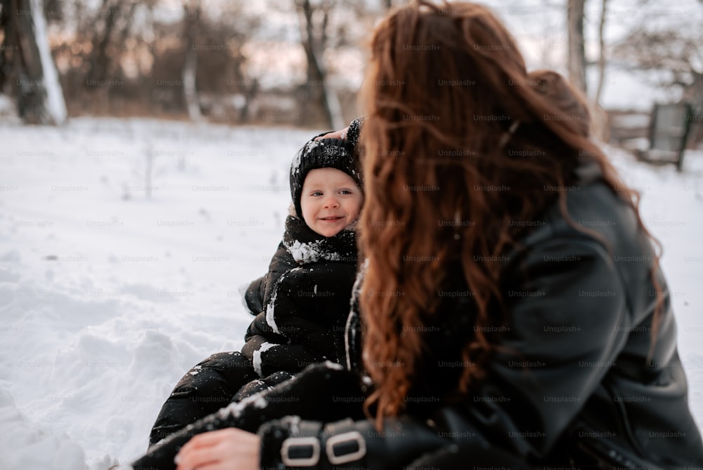 a woman sitting in the snow with a child
