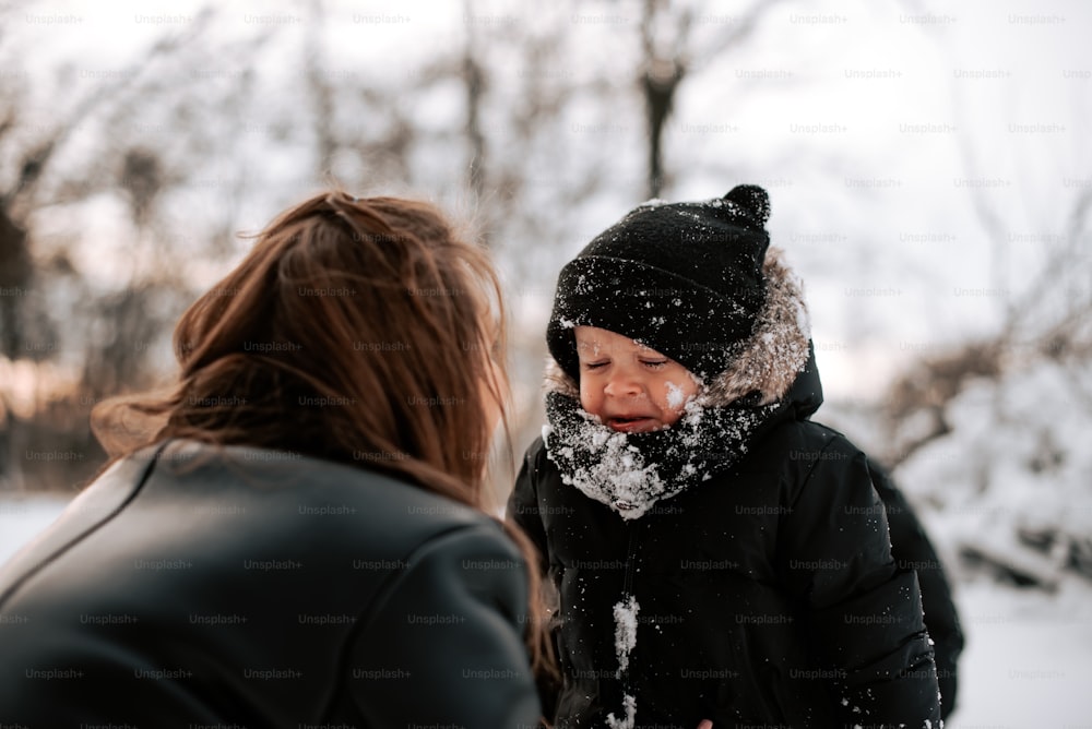 a woman standing next to a child in the snow