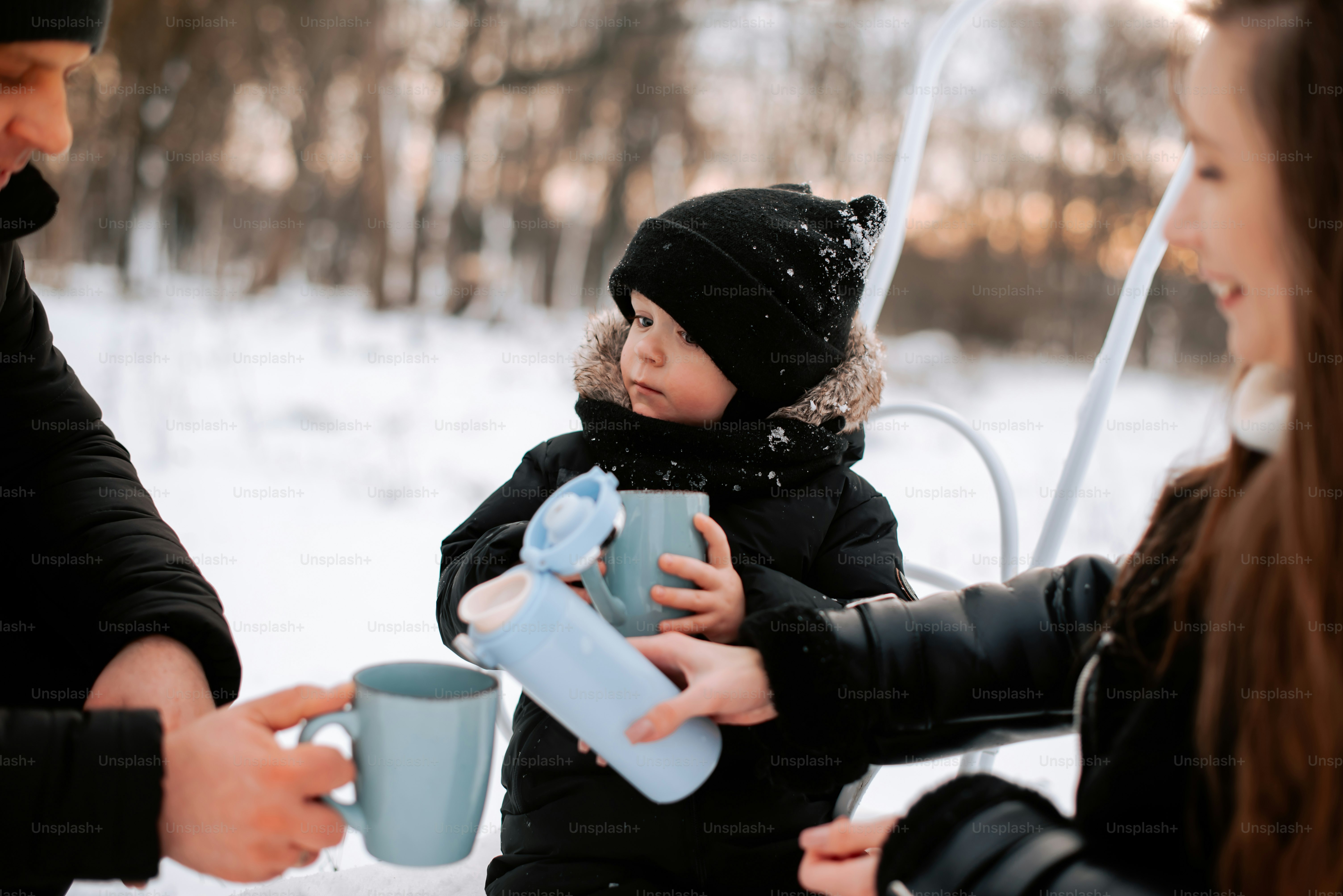 a little girl holding a blue cup while sitting on a bench