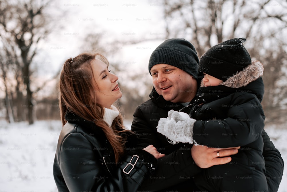 un uomo e una donna che tengono in braccio un bambino nella neve