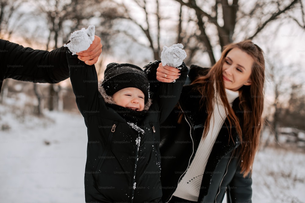 a woman and a man holding a baby in the snow