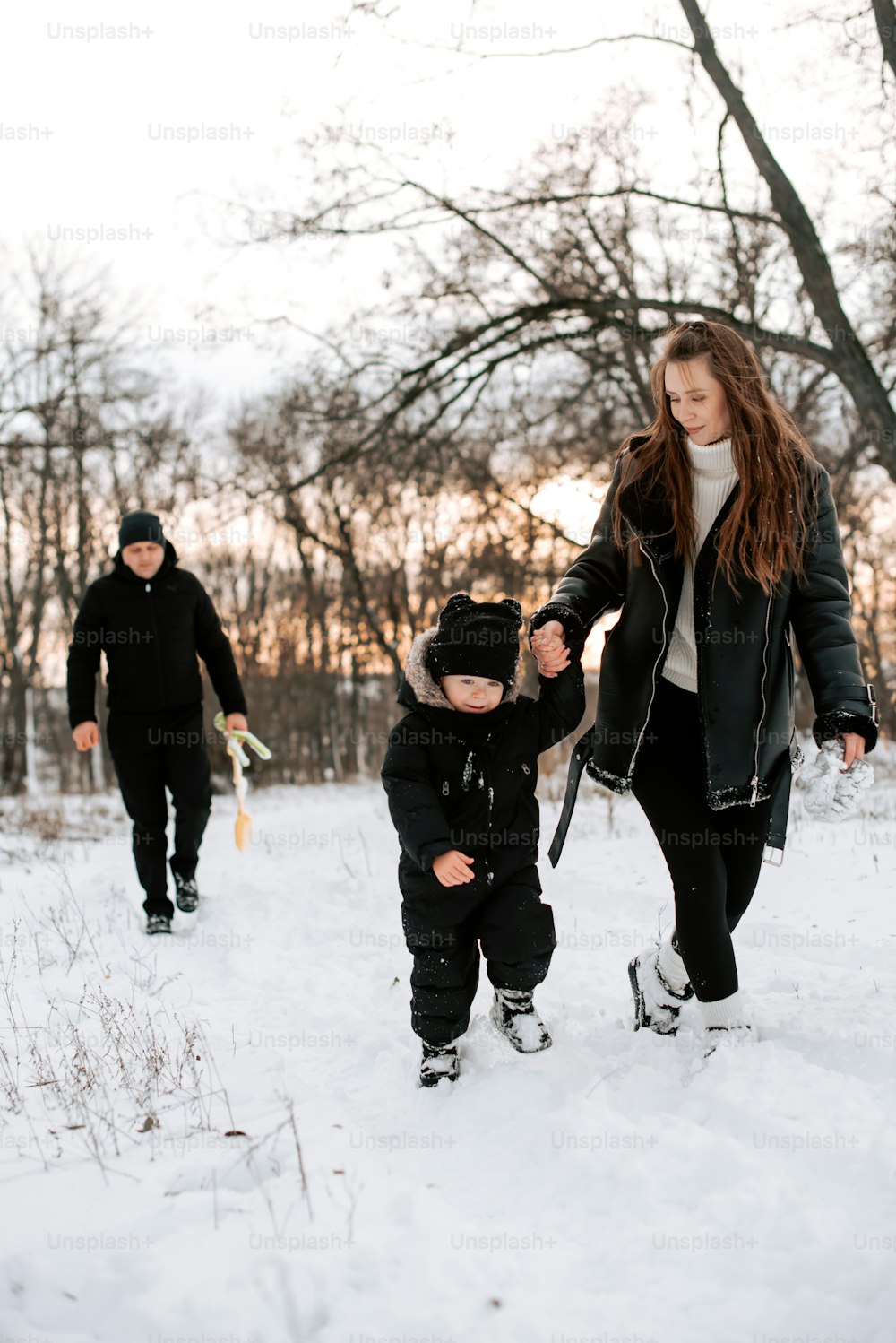 雪の中を歩く女性と子供