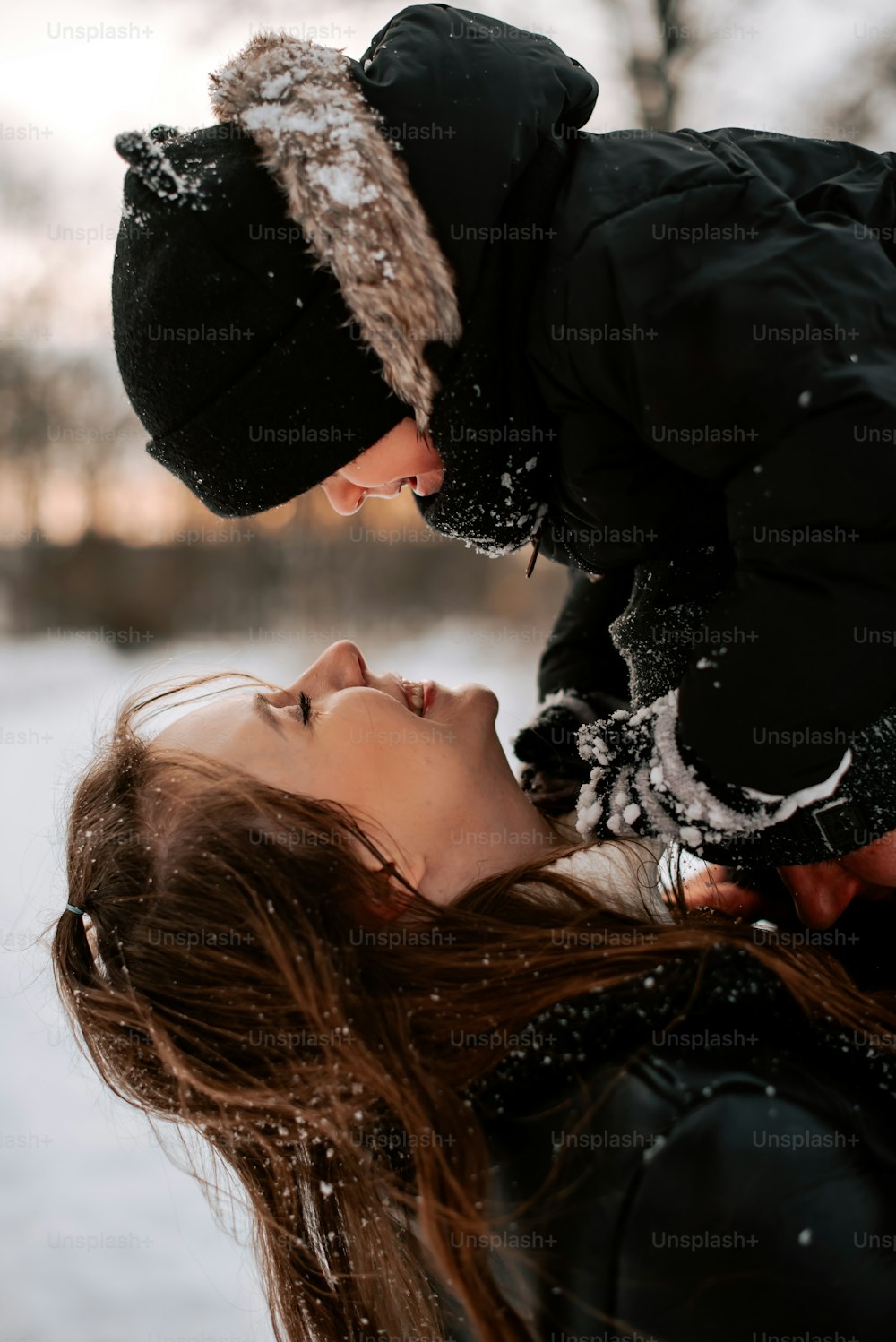 a woman is touching a man's face in the snow