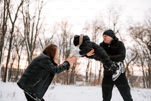 a man and a woman playing with a child in the snow