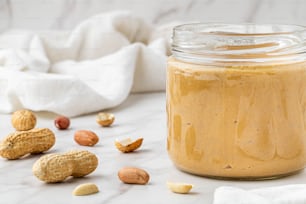 a jar of peanut butter surrounded by nuts