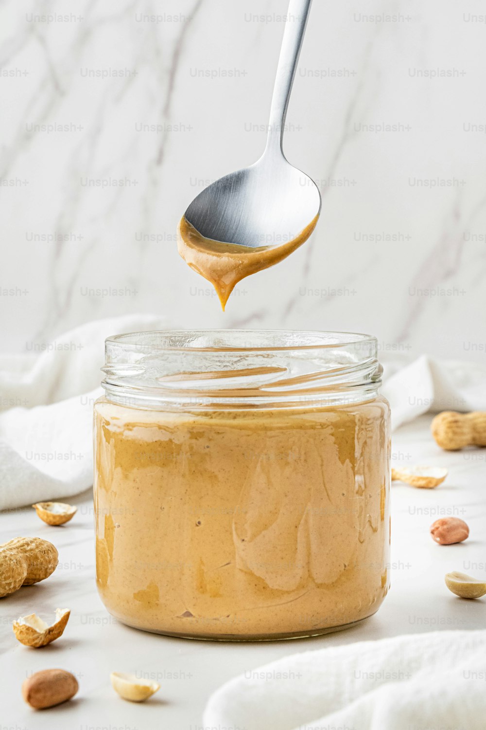 a spoon full of peanut butter on top of a jar