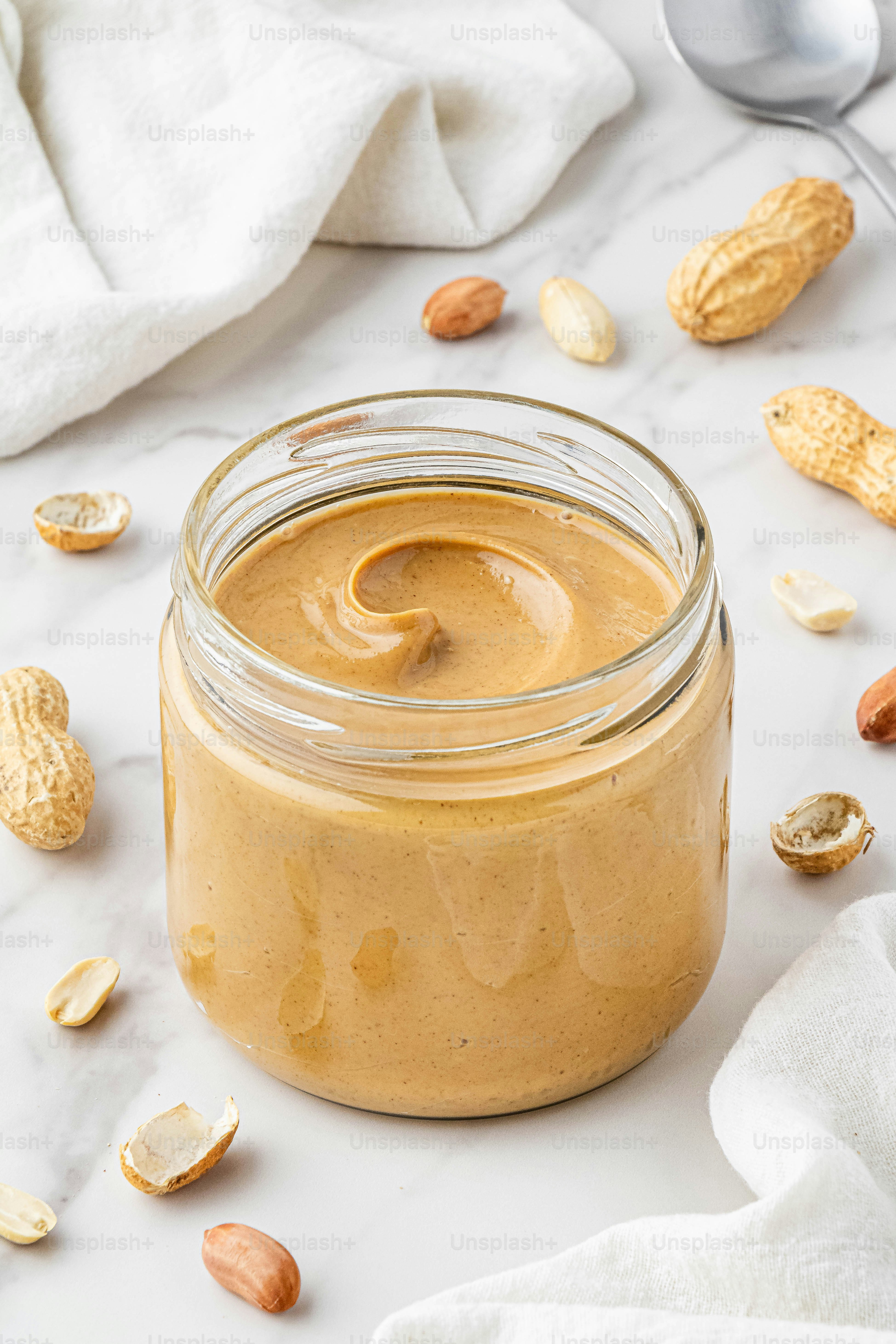 ein mit Erdnussbutter gefülltes Glas neben einem Löffel