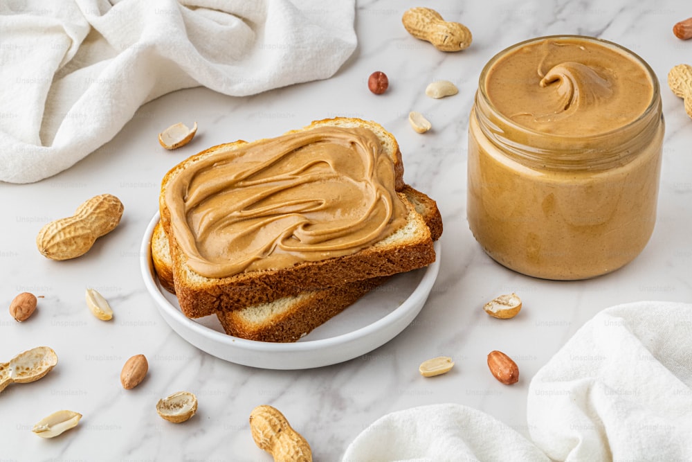 peanut butter spread on a piece of bread next to a jar of peanut butter